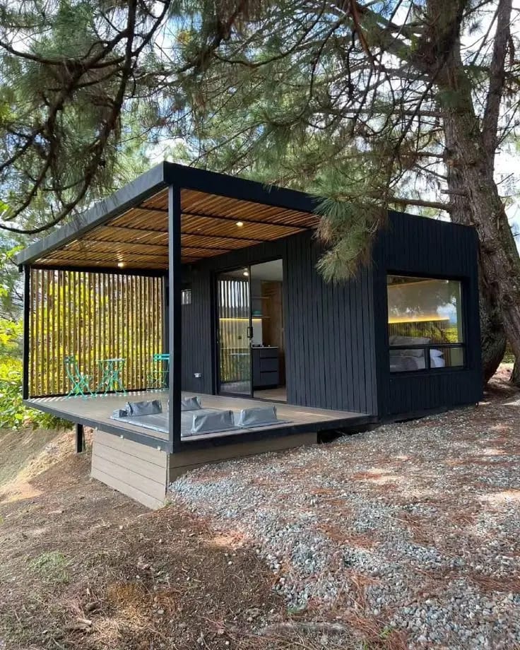 Modern black-clad cabin with a covered outdoor deck