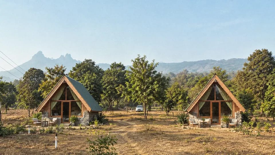 Two stone-base A-frame cottages with a mountain backdrop